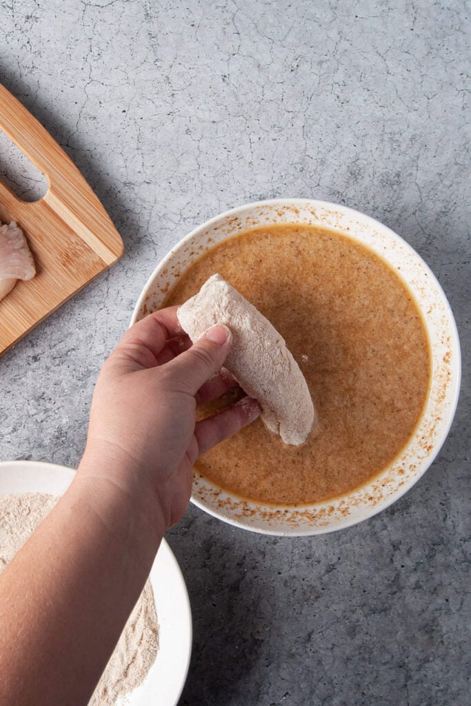 Dipping flour-coated halibut in beer batter.