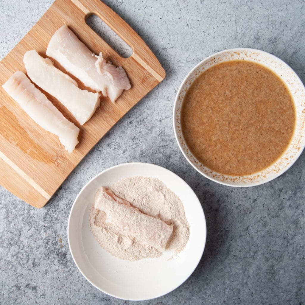 Covering halibut in flour to get ready to coat with batter.