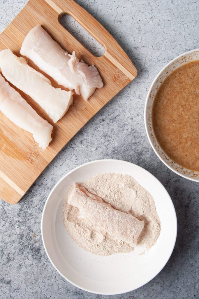 Covering halibut in flour to get ready to coat with batter.