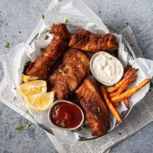 overhead photo of beer battered halibut with fires, dipping sauces, and lemon wedges