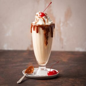 butterscotch milkshake with whipped cream and a cherry on top