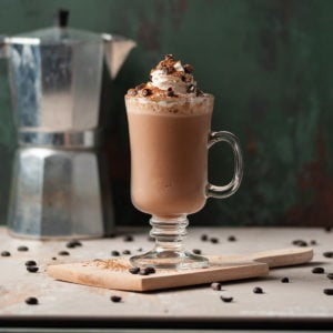 Wooden Cutting Board with Milkshake on Top Surrounded by Coffee Beans