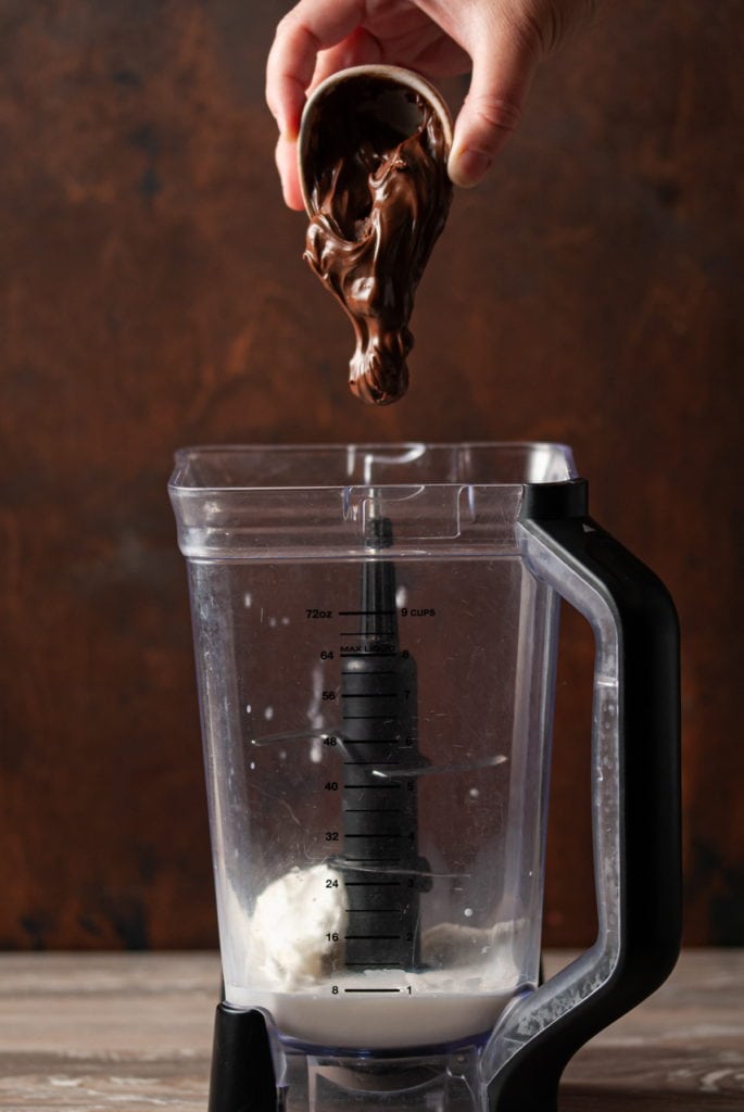 adding hazelnut spread to a blender with ice cream and milk