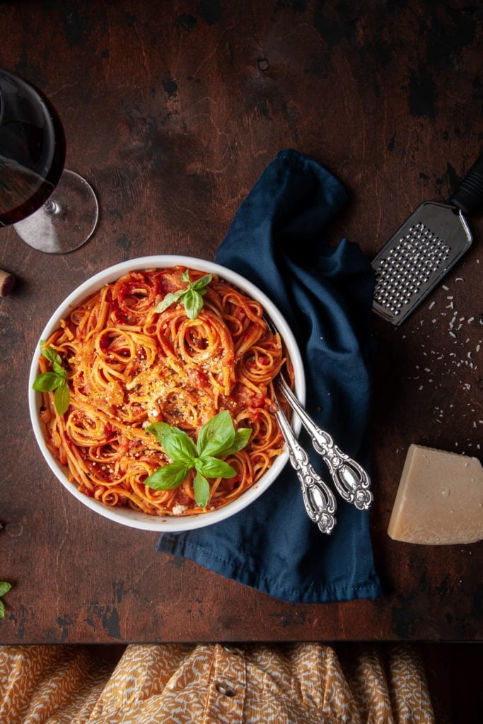 overhead shot of pasta with tomato sauce and woman's dress whowing