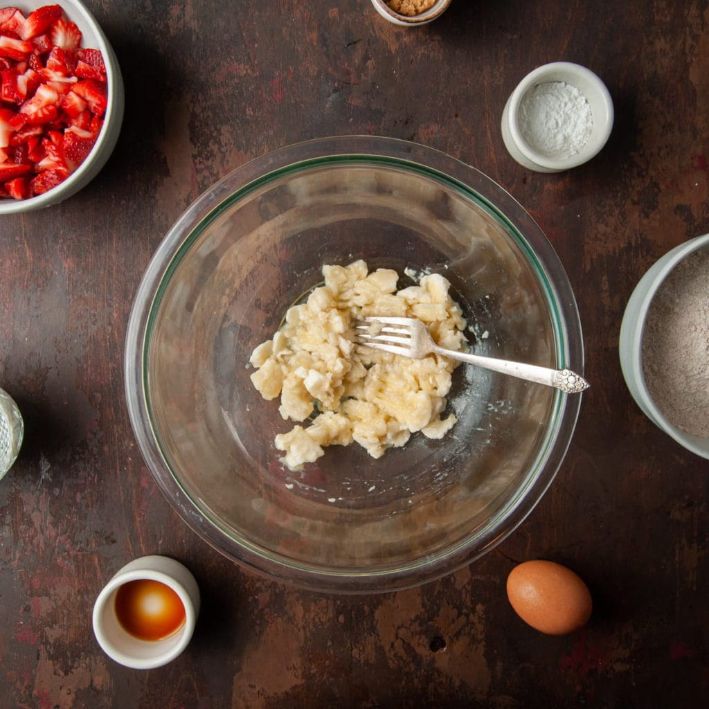 mashed banana in a large mixing bowl with a fork