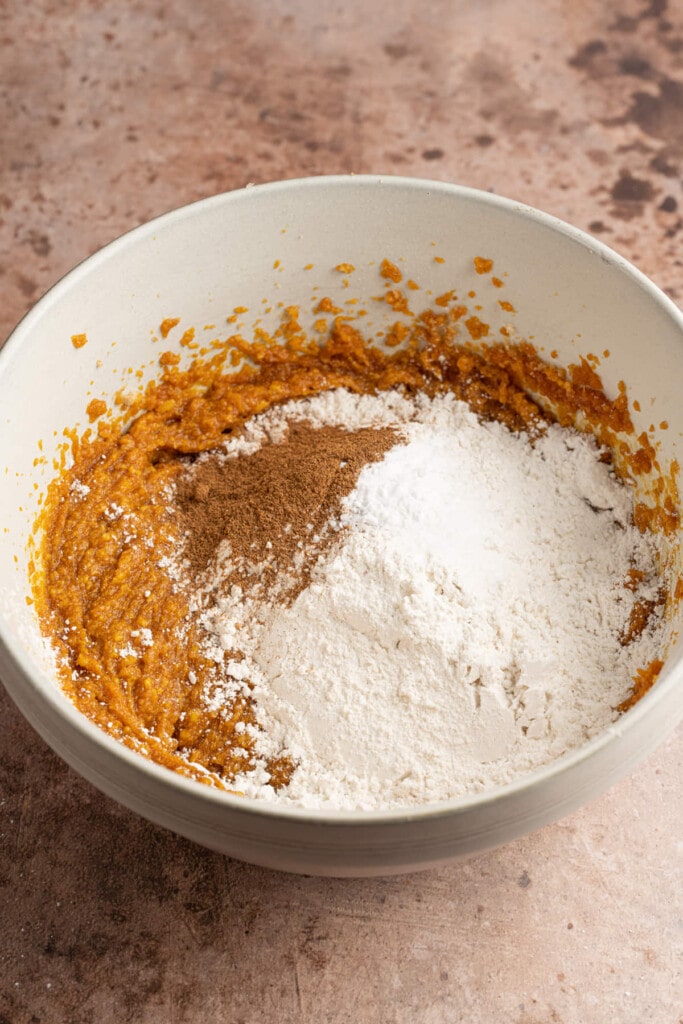 Adding flour, salt, baking soda, and pumpkin pie spice to vegan cookie dough