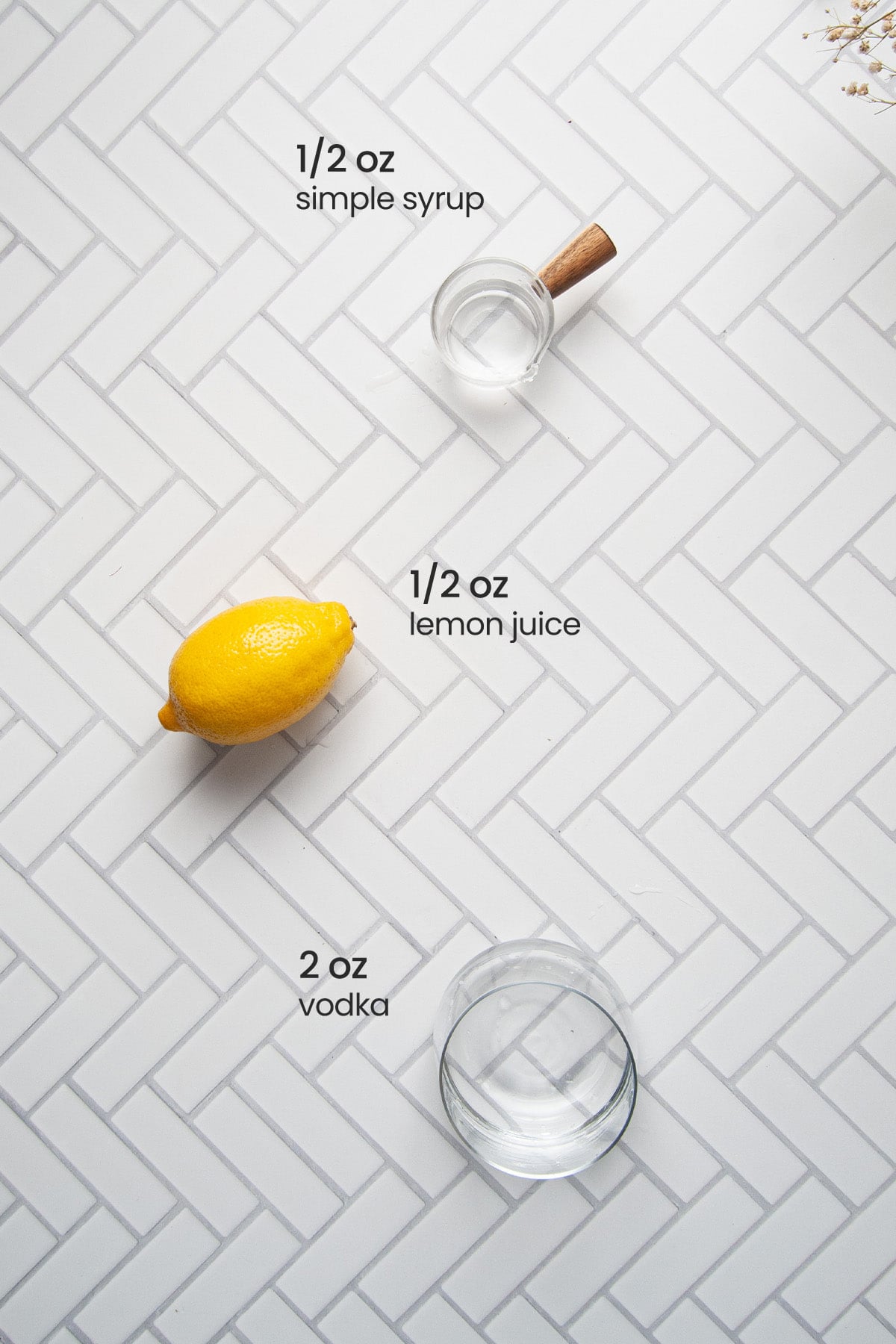 Overhead view of the ingredients for a vodka sour - ingredients for vodka sour - simple syrup, lemon, and vodka.