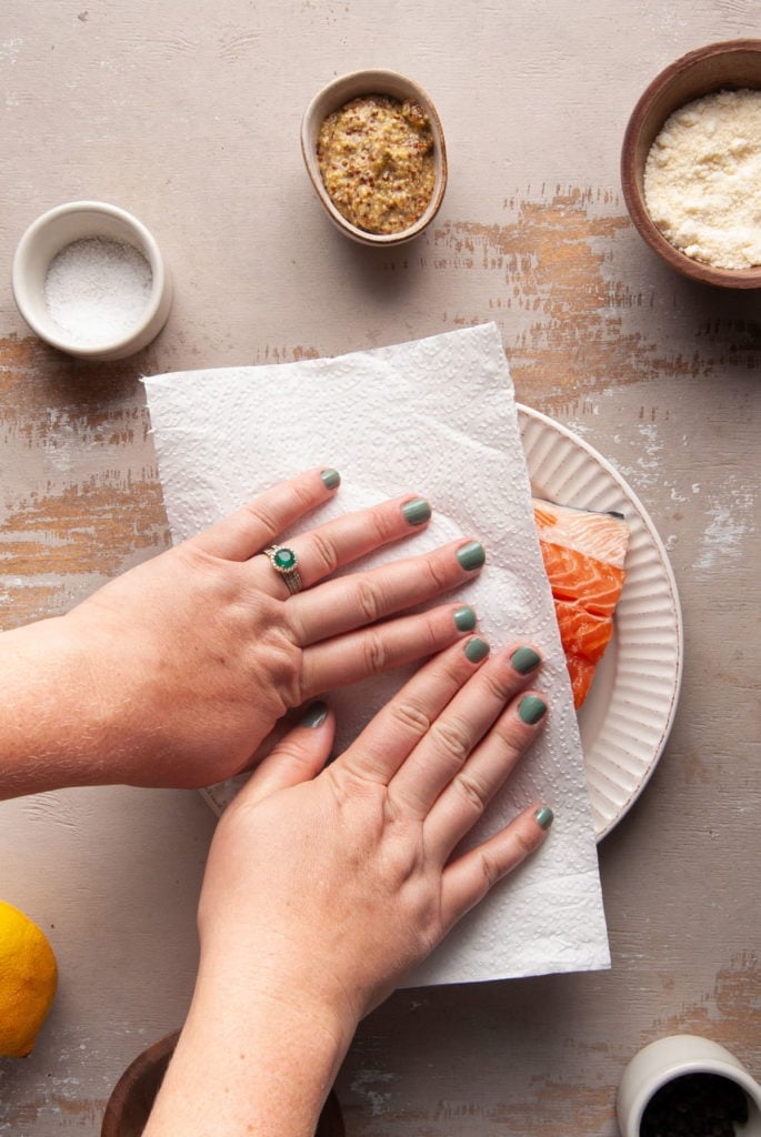 patting salmon dry with a paper towel