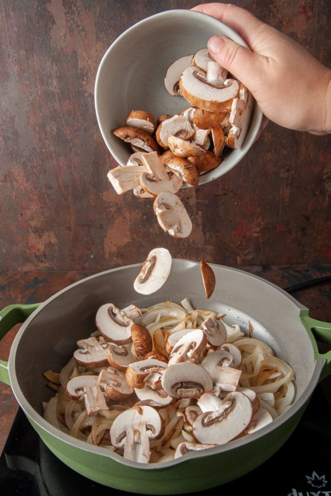 adding sliced mushrooms to pan of caramelized onions