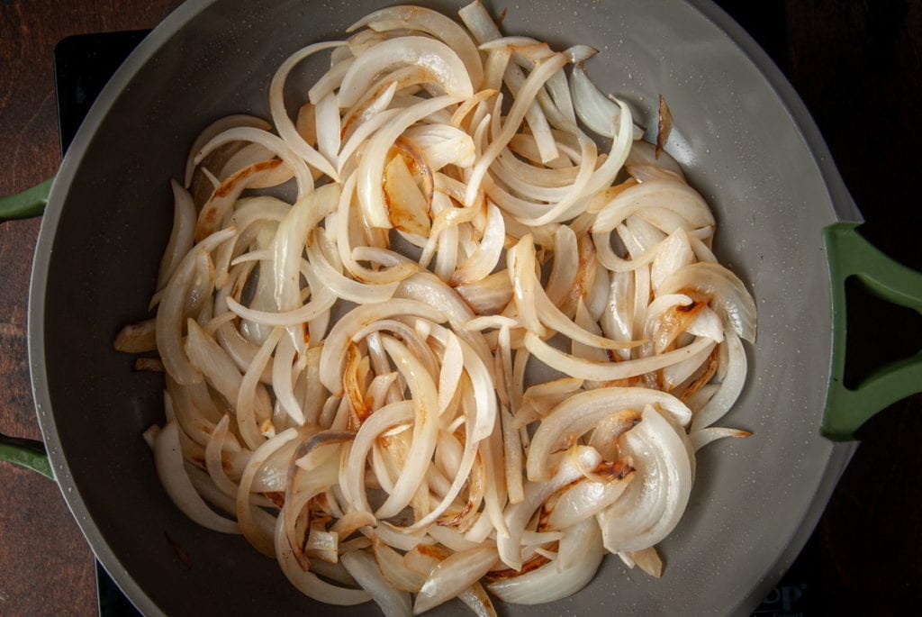sliced onions caramelizing in a pan