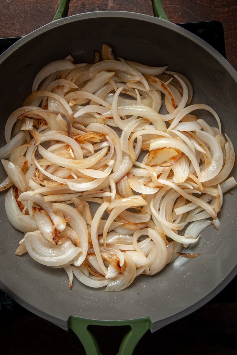 Sliced onions caramelizing in a pan.