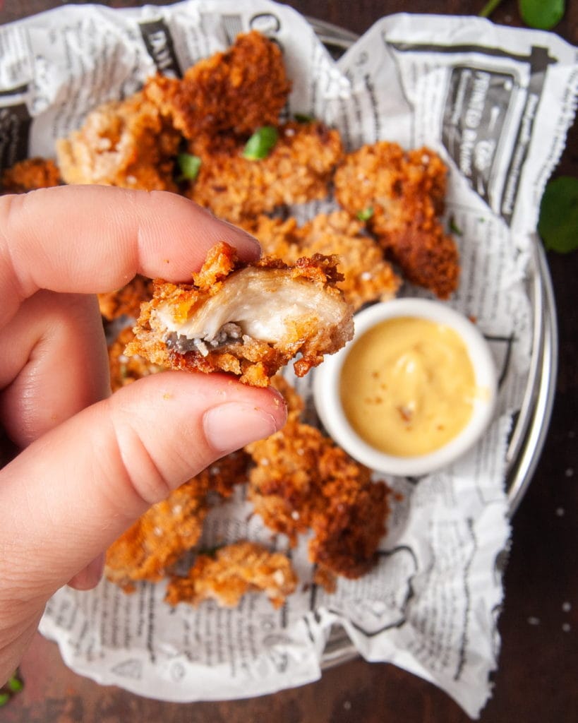 hand holding a fried oyster mushroom with bite taken out