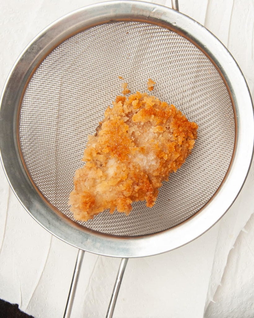 using a sieve or skimmer to remove fried mushroom from hot oil