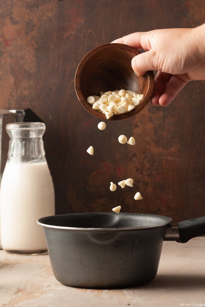 pouring white chocolate chips into a small pot