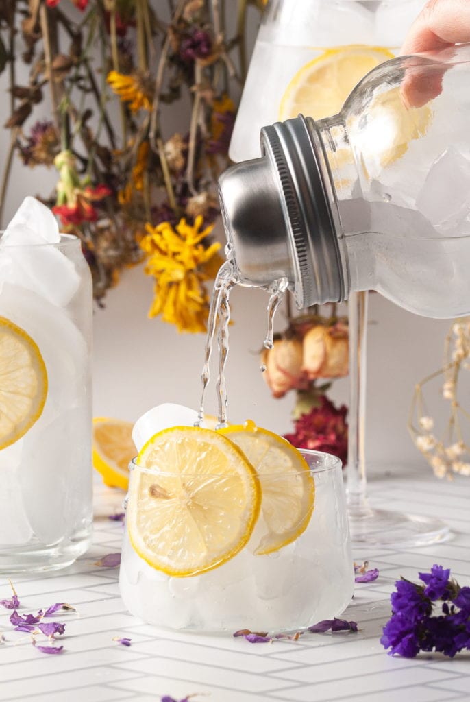 pouring lemon sour out of cocktail shaker and into a glass