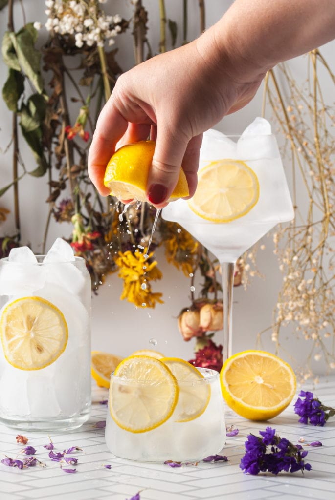 squeezing lemon over a vodka sour to give it extra citrus