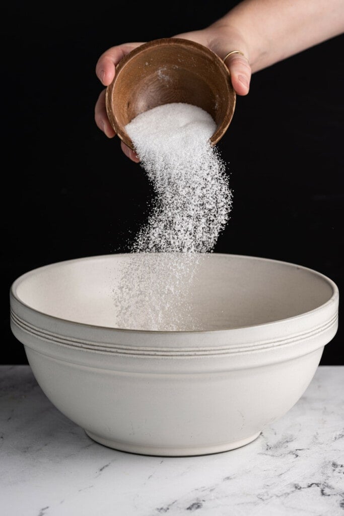 Adding sugar to large mixing bowl to cream with banana, peanut butter, and oil