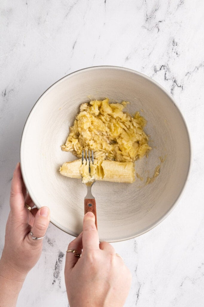 Mashing overripe banana with a fork to add to muffin batter