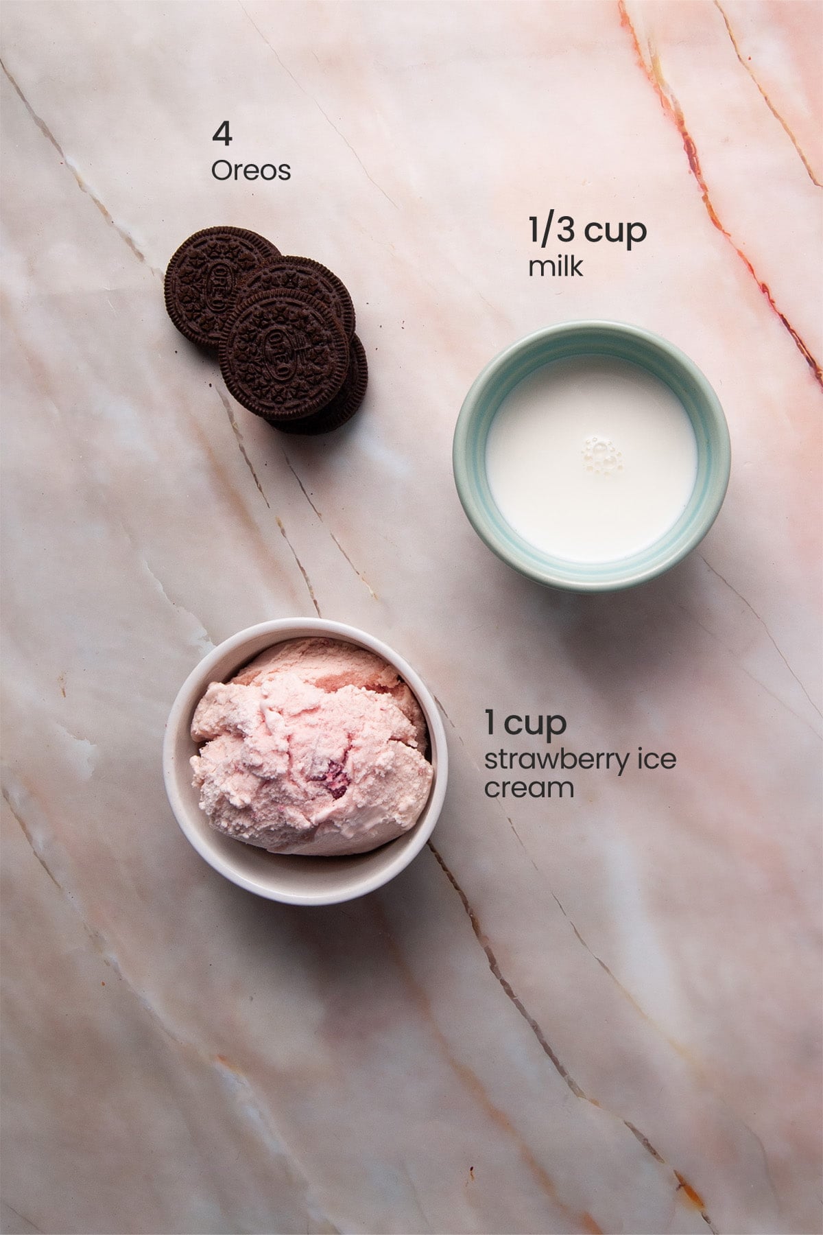 Overhead view of the ingredients needed for strawberry Oreo milkshake - Oreos, milk, and strawberry ice cream.