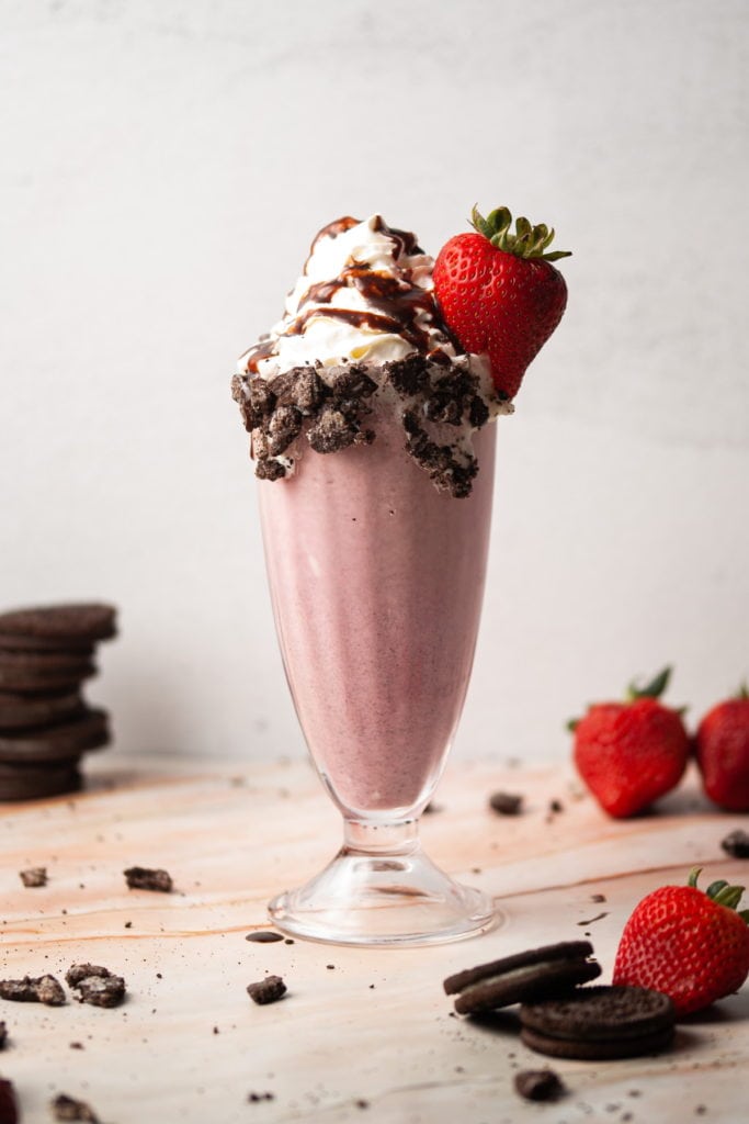 pink milkshake with whipped cream and a strawberry on top