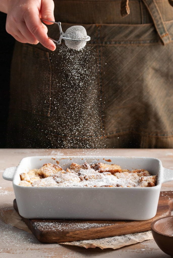 dusting powdered sugar over vegan bread pudding