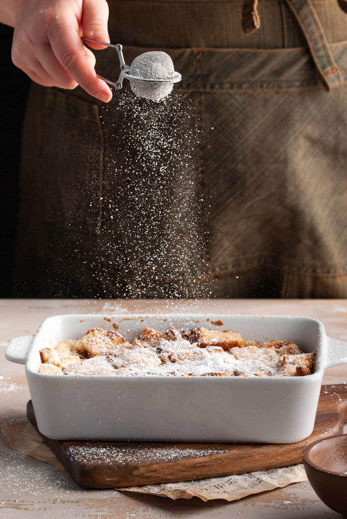 Dusting powdered sugar over vegan bread pudding.