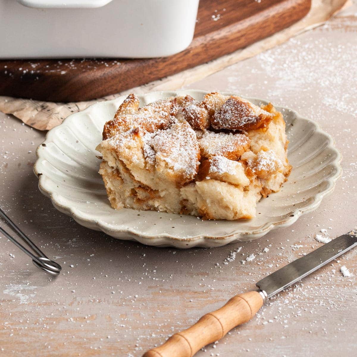 slice of vegan bread pudding on a plate with knife in front