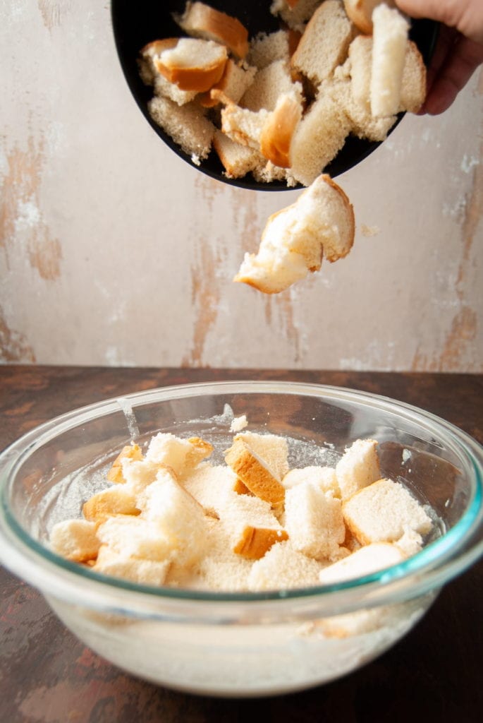 adding cubed bread to a large mixing bowl