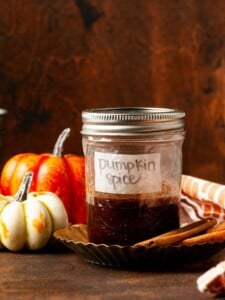 pumpkin spice simple syrup in a sealed jar surrounded by little pumpkins