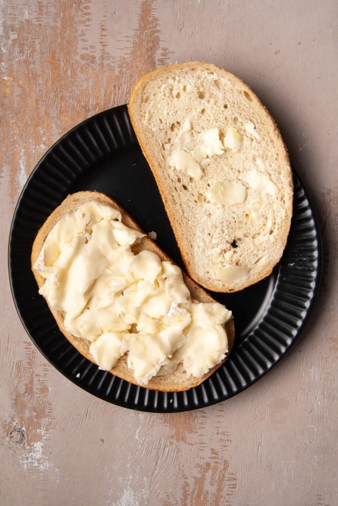 Generous amount of brie on buttered bread to make a grilled cheese sandwich with apple.