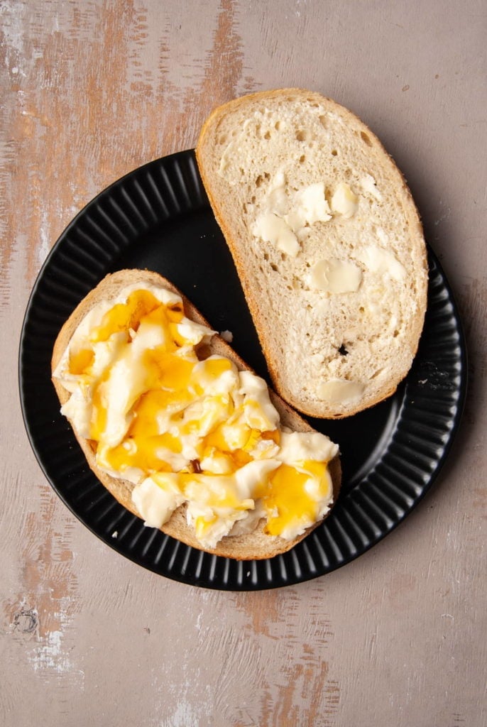 Adding even layer of honey on top of layer of brie cheese.