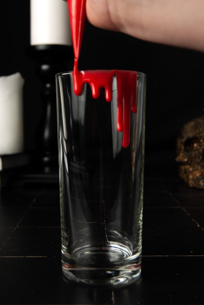 piping fake edible blood onto rim of cocktail glass