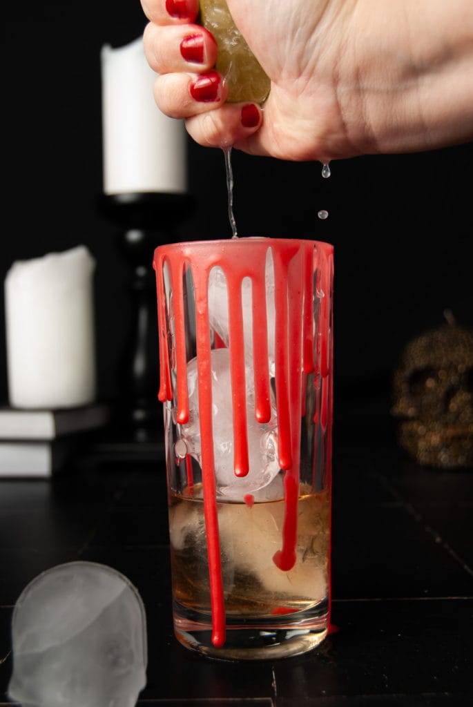 squeezing lime into a halloween cocktail