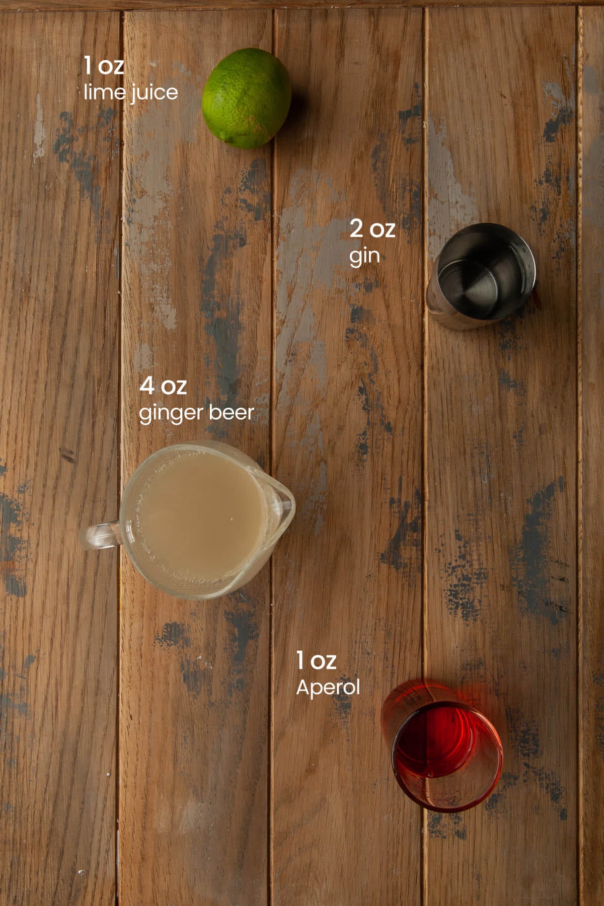 Everything you need to make an Aperol Gin cocktail including lime juice, gin, ginger beer, and Aperol.