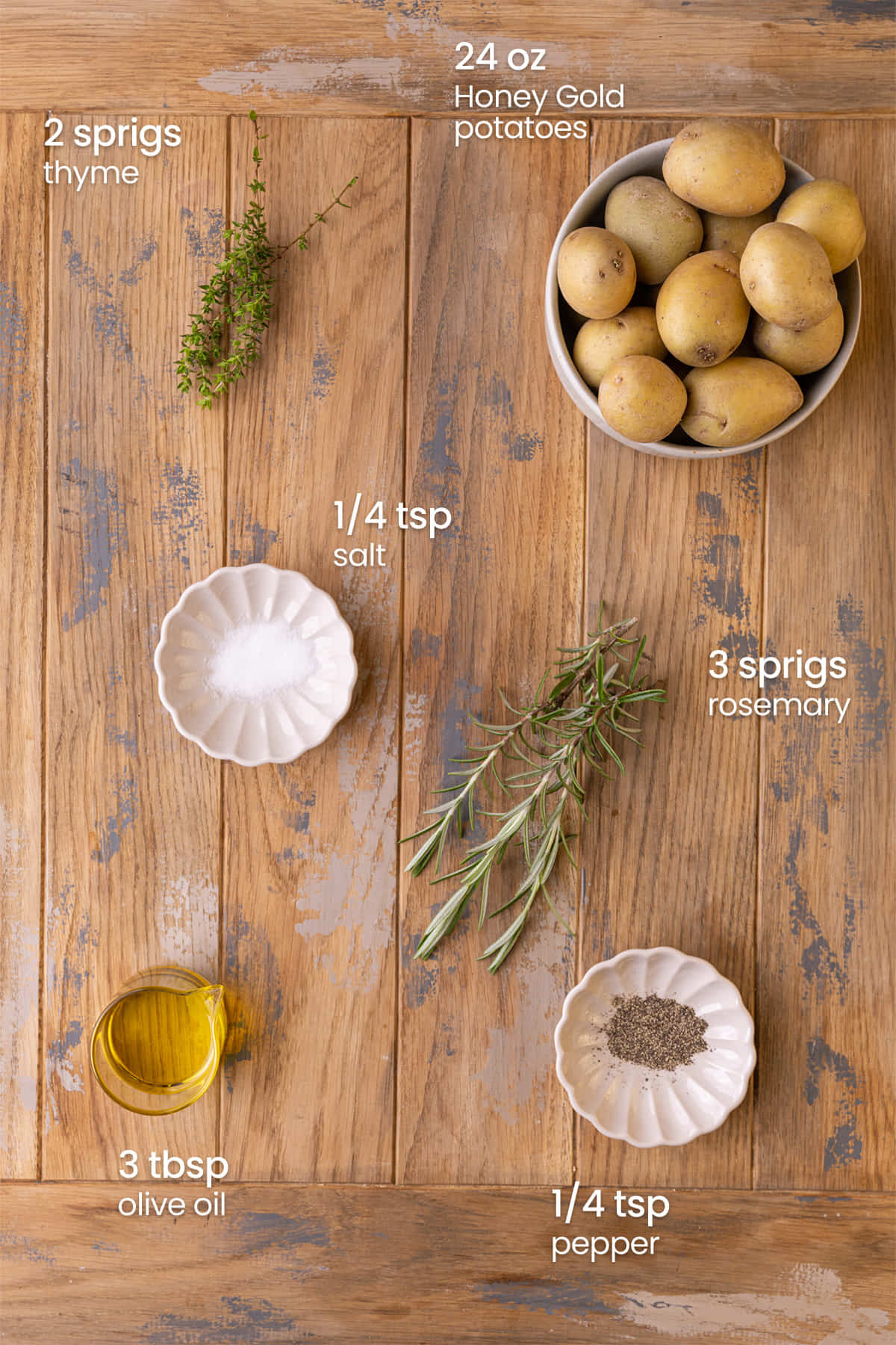 Everything needed to make Roasted Honey Gold Potatoes including the honey gold potatoes, olive oil, rosemary, thyme, salt, and pepper.