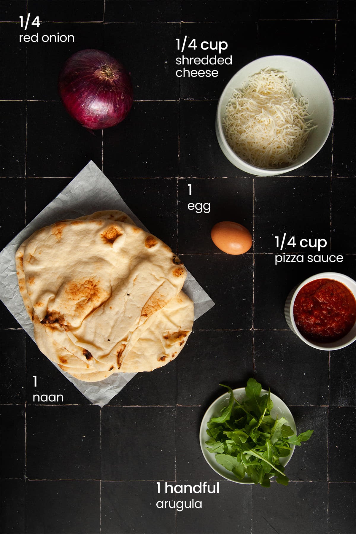 Everything you'll need to make vegetarian naan breakfast pizza including naan bread, marinara sauce, Italian cheese blend, arugula, red onion, and an egg.
