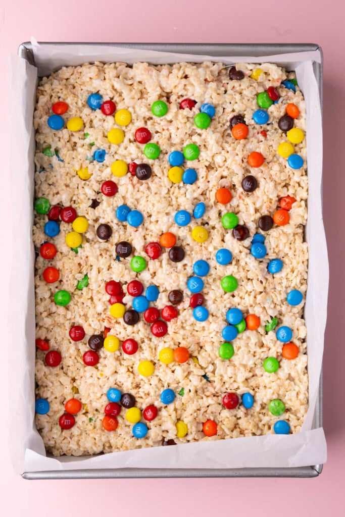 M&M Rice Krispies pressed into a 9x13-inch baking sheet with M&M's throughout and on top. 