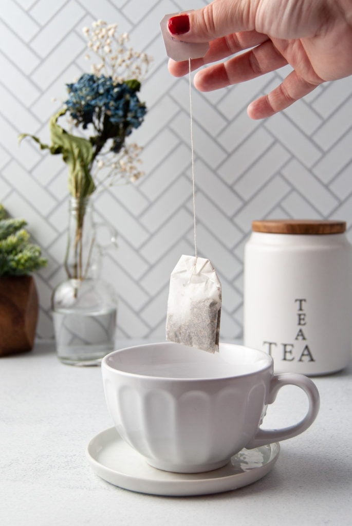 dipping tea bag into teacup with hot water