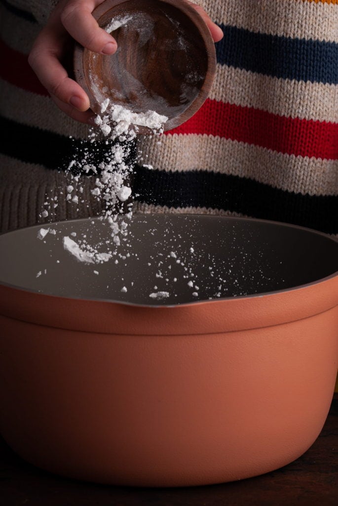 Adding flour to a pot to make a roux.