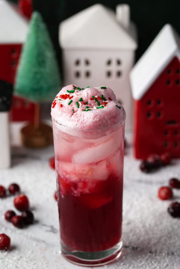Gin and Cranberry Christmas Cocktail surrounded by snow and Christmas townscape
