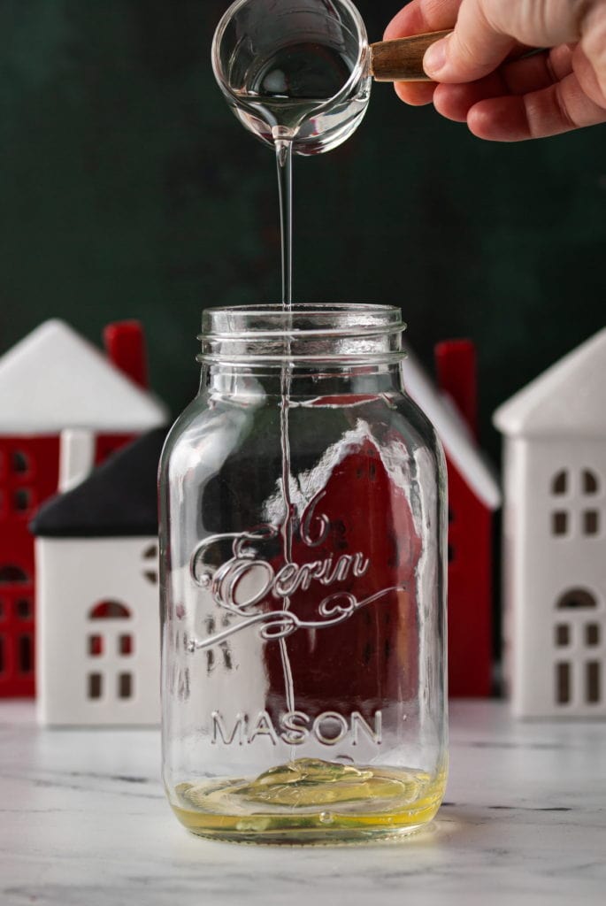 adding simple syrup to cocktail shaker with festive holiday background