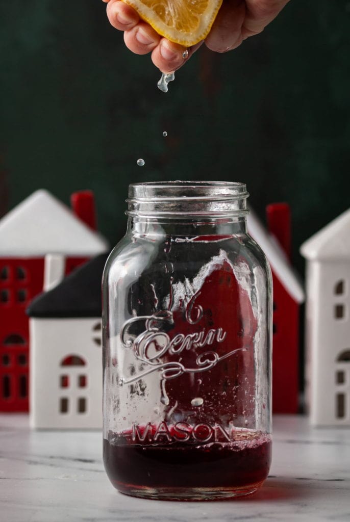 squeezing lemon juice into shaker with christmas cocktail