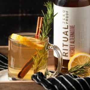 closeup of non-alcocolic hot toddy on a tray with ritual bottle behind it