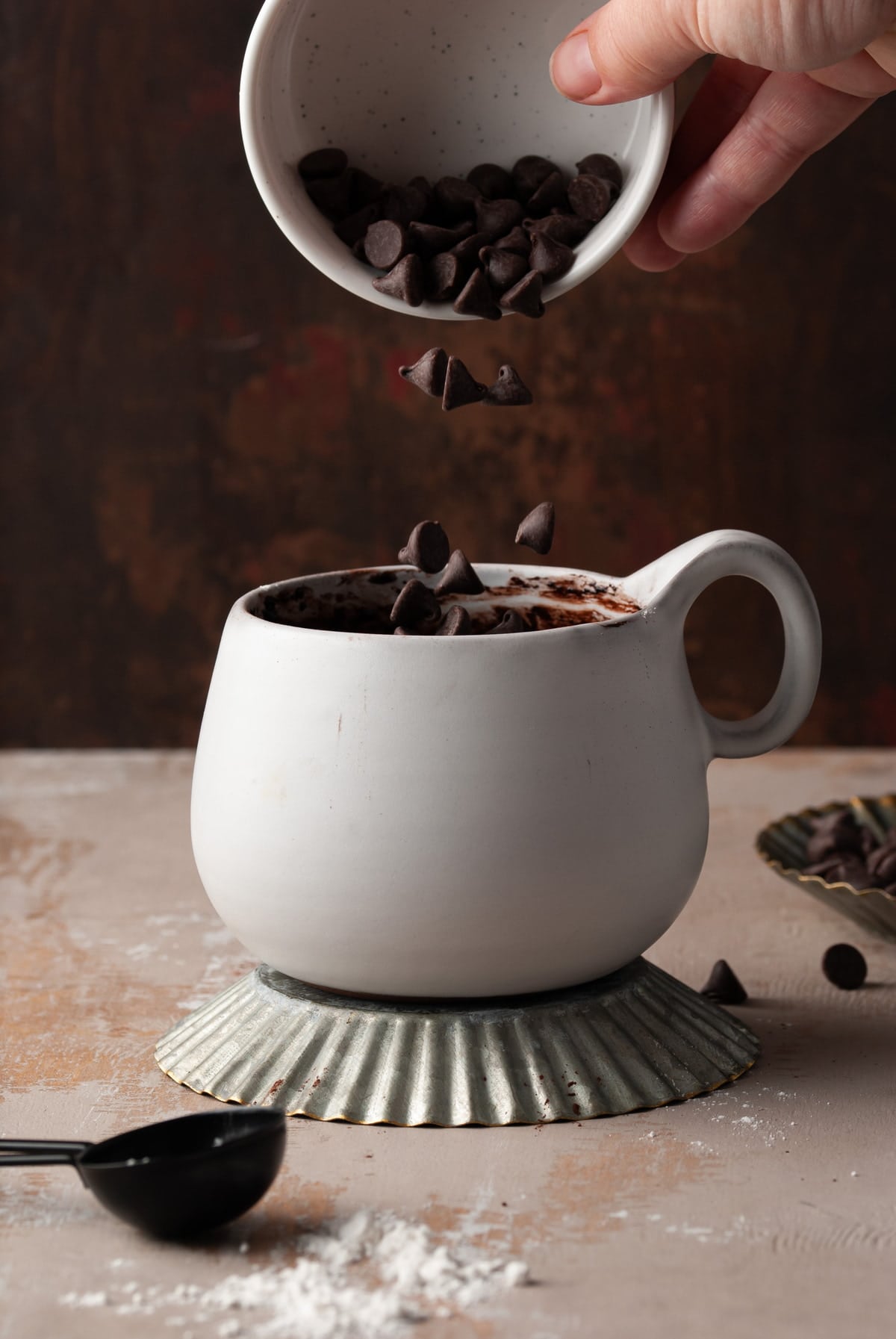 pouring chocolate chips into white mug