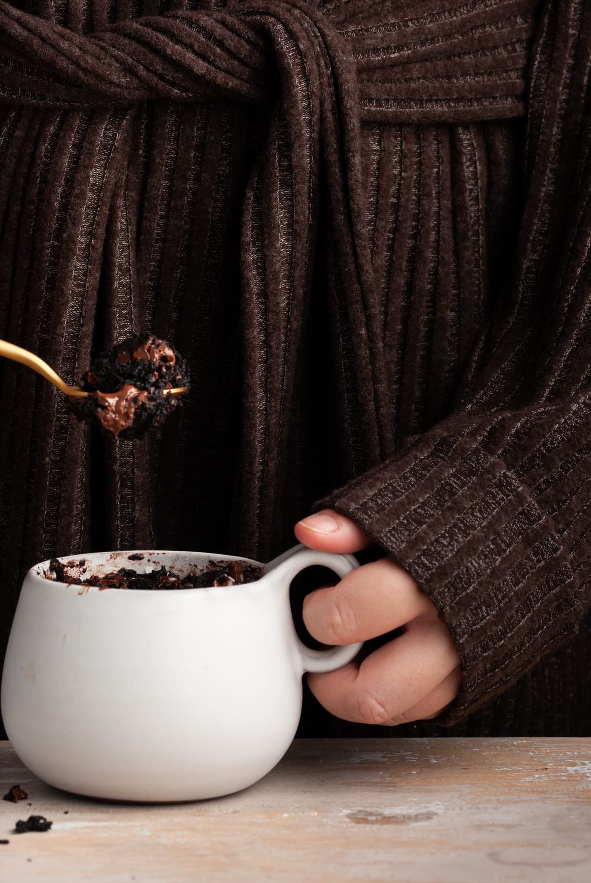 Taking a bite of vegan mug brownie on a gold spoon