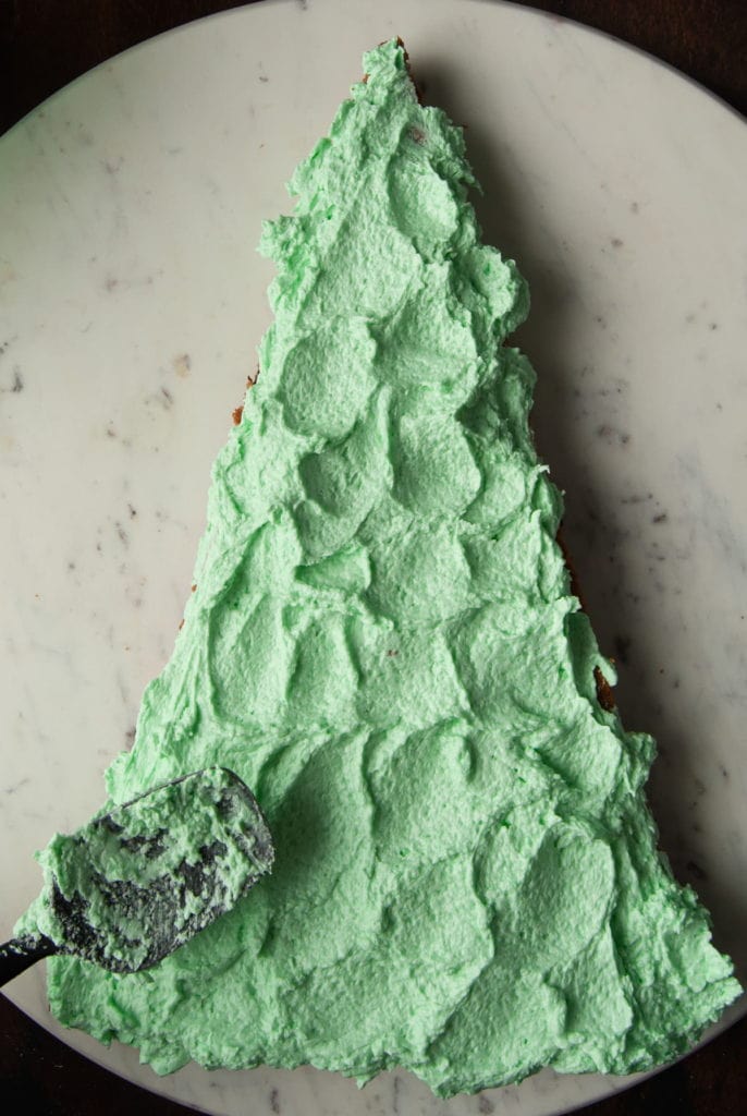 adding green white chocolate ganache to triangle shaped cookie cake