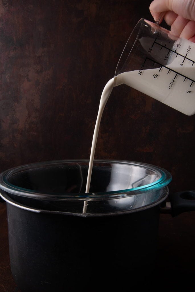 adding heavy cream to a double boiler to heat