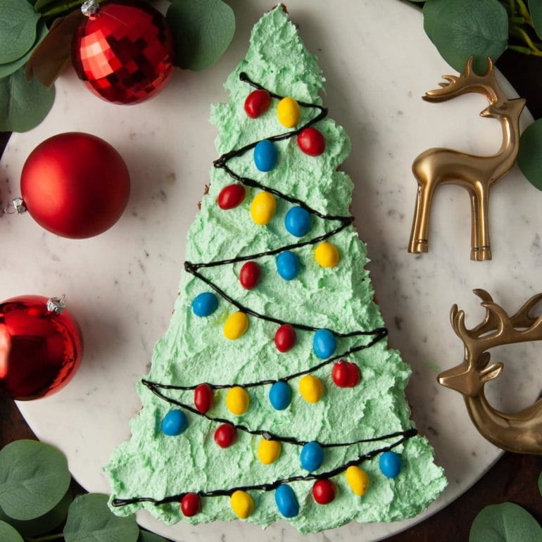 Christmas cookie cake surrounded by gold reindeer and red ornaments