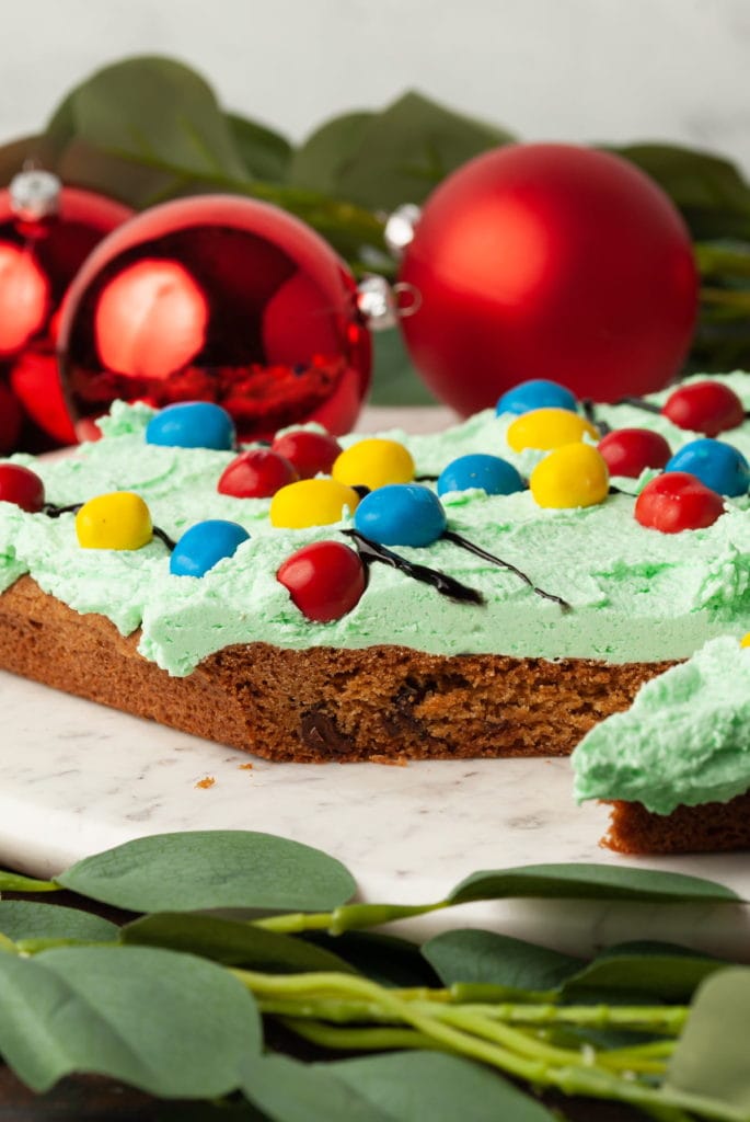 sliced christmas cookie cake with red ornaments in the background