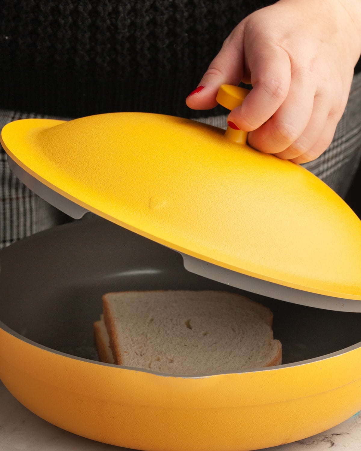 Adding cover to hot pan with grilled cheese in it.